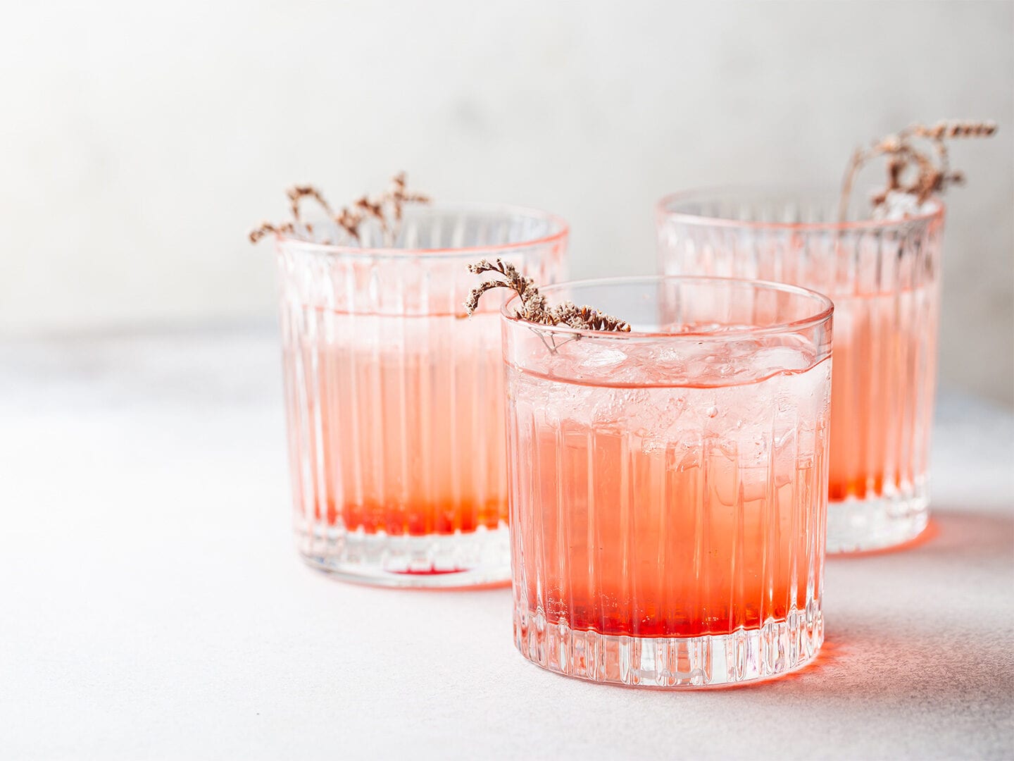Drei Cocktails mit orangener Flüssigkeit auf dem Tisch