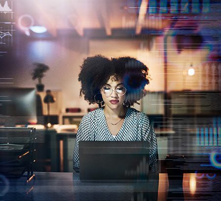 Eine Frau sitzt im Büro am Laptop und arbeitet mit Daten
