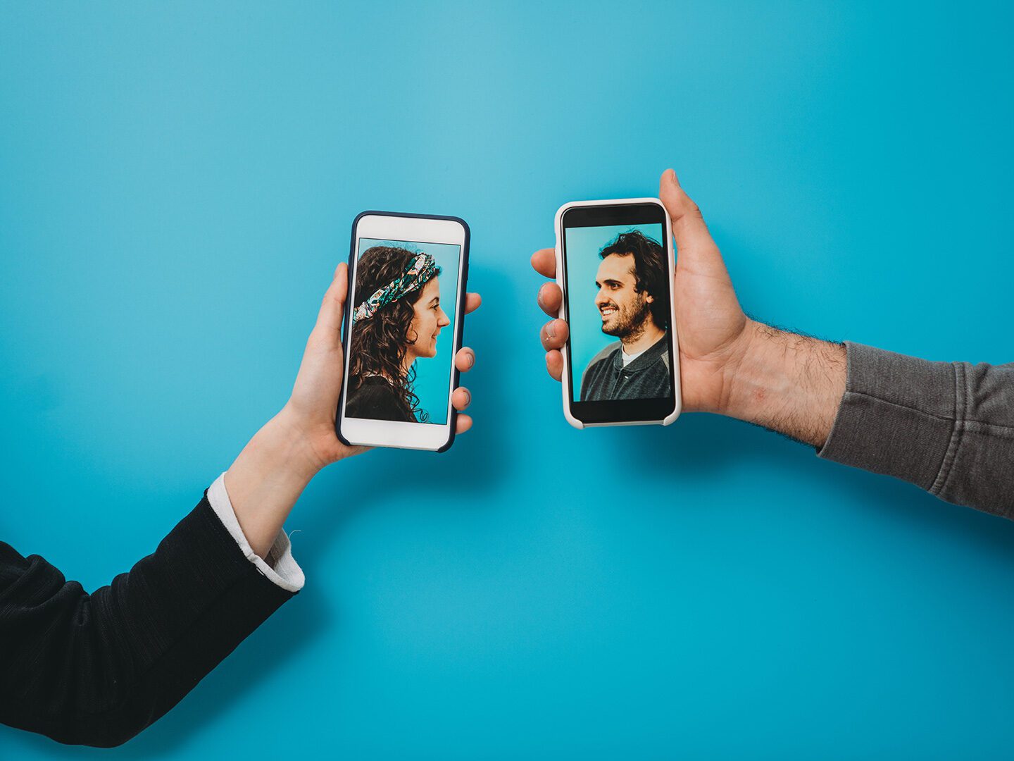 zwei Personen halten Smartphones mit Bildern von 2 Personen, die miteinander sprechen