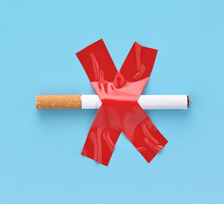 eine Zigarette wurde mit einem X aus rotem Klebeband festgemacht; Symbol für Rauchverbot und Rauchentwöhnung