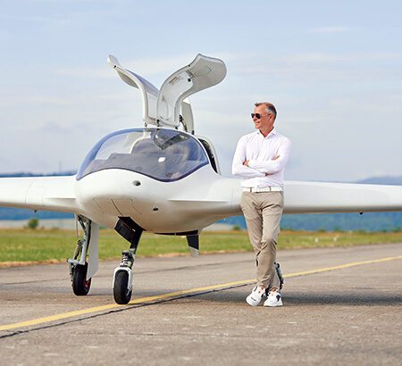 Ein Mann in einem weißen Hemd steht vor einem Nurflügler Flugzeug.
